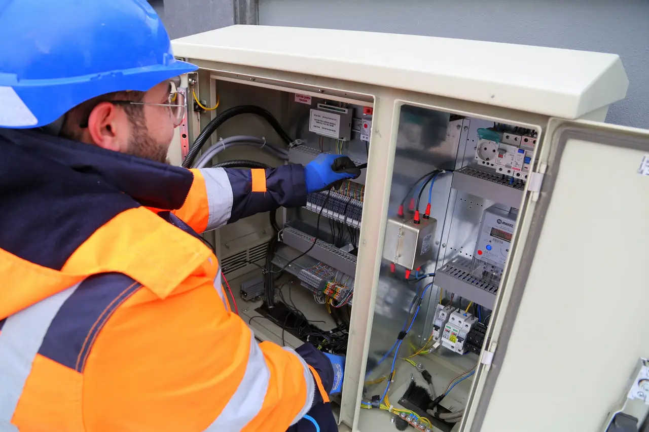 An electrician wiring a residential breaker panel with the cover removed