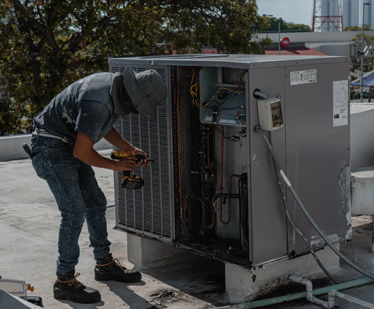 An HVAC technician checking the refrigerant gauges on an outdoor condenser unit